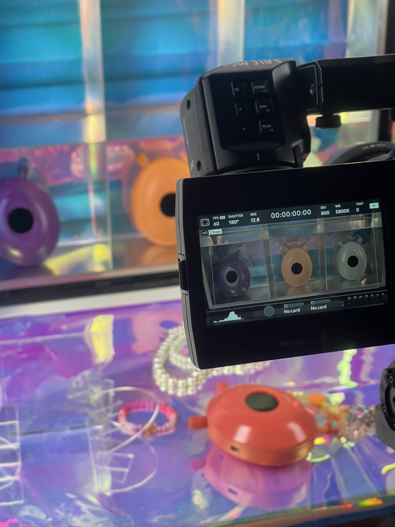 The film set from another angle: the camera monitor above the orange device on iridescent foil. Funke (2026) by Nickii Schamborski.