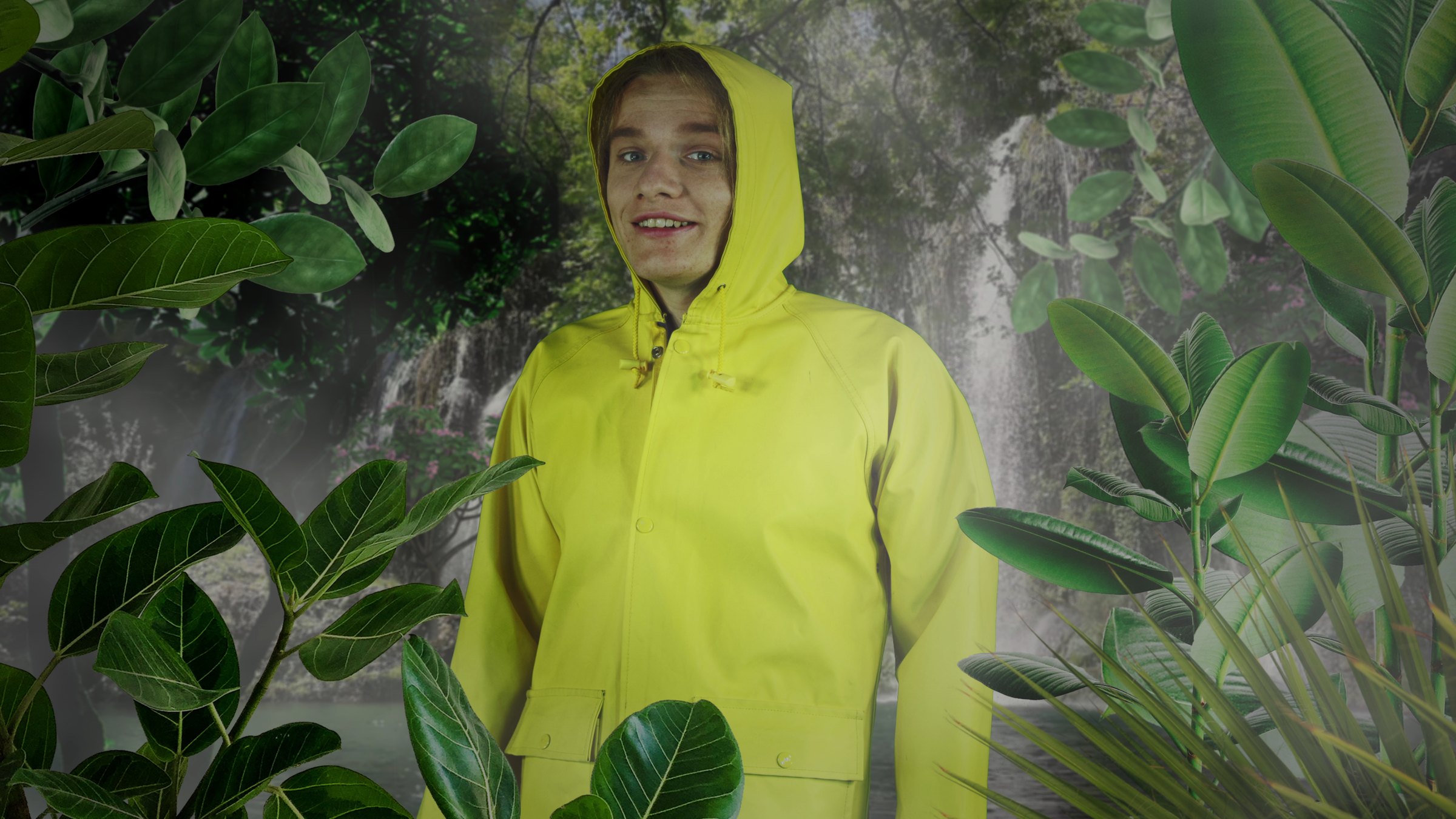 A person in a yellow hooded raincoat smiles at the camera, surrounded by large green leaves and a misty waterfall backdrop. Systemchange (2020) by Nickii Schamborski.